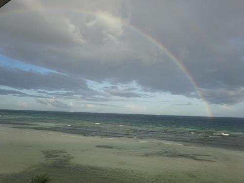 a rainbow over the beach with the ocean at House Rapunzel in Oslob