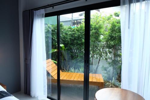 a room with a sliding glass door with a bench outside at The Besavana Phuket - SHA Extra Plus in Phuket Town