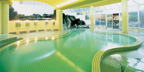 a large swimming pool in a building with a swimming pool at Itoen Hotel in Ito