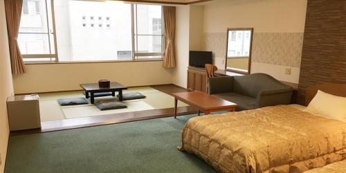 ein Schlafzimmer mit einem Bett, einem Sofa und einem TV in der Unterkunft Itoen Hotel in Ito