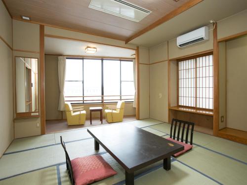 a room with a table and chairs and windows at Kindayu in Shibukawa