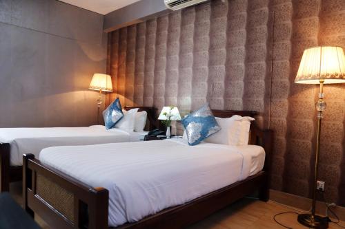 two beds in a hotel room with two lamps at Civic Inn in Dhaka