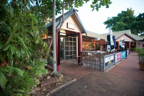 a building with a patio with a table and umbrella at Roebuck Bay Hotel in Broome