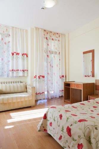 a bedroom with a bed and a couch and curtains at Family Hotel Gorski Kut in Rilski Manastir