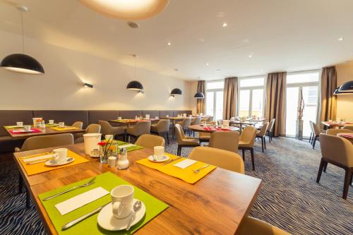 Altstadthotel Kneitinger, Abensberg في آبنسبرغ: غرفة طعام مع طاولات وكراسي وطاولة