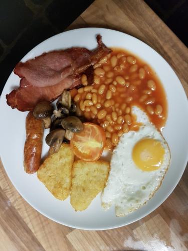 a plate of breakfast food with eggs beans and bacon at Roosecote Guest House in Barrow in Furness