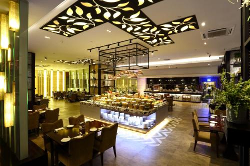a restaurant with tables and chairs and a bar at Cambridge Hotel Medan in Medan