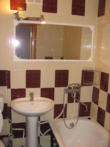 La salle de bains est pourvue d'un lavabo, d'un miroir et d'une baignoire. dans l'établissement Bon Apart Avangard, à Mykolaïv