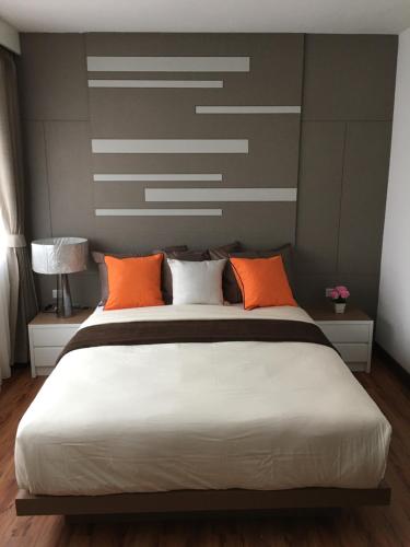 a bedroom with a large white bed with orange pillows at Samui Paca place in Mae Nam