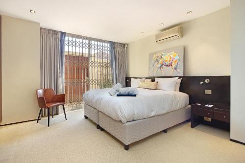 a bedroom with a large bed and a chair at Glen Sunsets Villa by Totalstay in Cape Town
