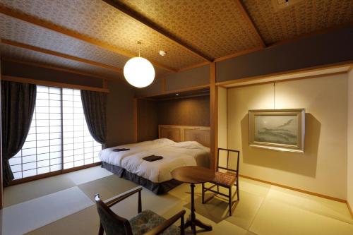 a bedroom with a bed and a table and a window at Yufuin Souan Kosumosu in Yufuin