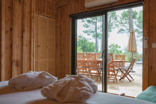 - une chambre avec un lit et une vue sur une terrasse dans l'établissement Ô Lac, à Lacanau