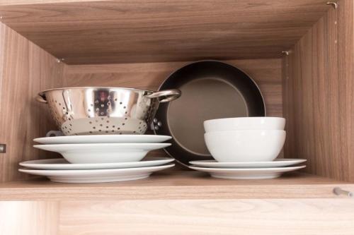 a shelf with plates and a pot and bowls at Apartments Sissi & Franz in Merano