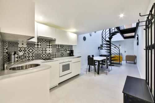 une cuisine avec des armoires blanches et une table avec des chaises dans l'établissement Le loft de Cathy 1, à Honfleur