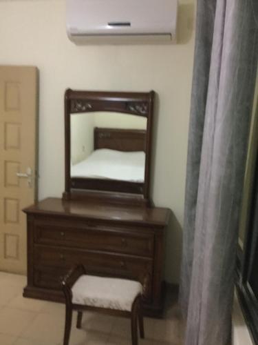 een dressoir met een spiegel en een stoel in een kamer bij Julmarte in Lomé