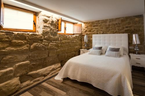 a bedroom with a stone wall with a bed and windows at La Casona de Alútiz & Bodega in Samaniego