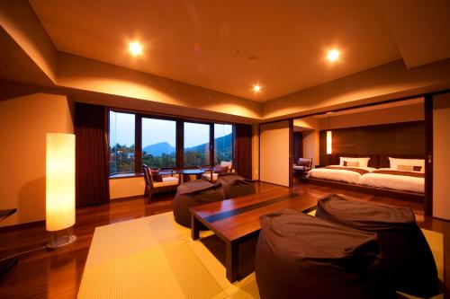 ein Wohnzimmer mit einem Bett, einem Sofa und einem Tisch in der Unterkunft Resorpia Beppu in Beppu
