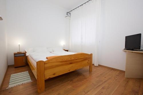 ein Schlafzimmer mit einem Holzbett und einem TV in der Unterkunft Zoli Apartmanok-Anita Kölcsey 34-36 in Hajdúszoboszló