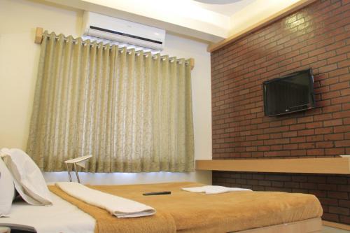 a bedroom with two beds and a tv on a brick wall at Hotel Sai Gurusthan in Shirdi