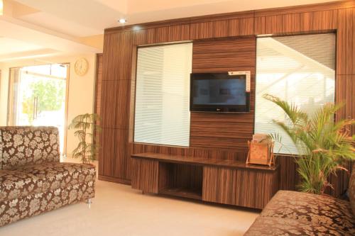 a living room with a flat screen tv and a window at Hotel Sai Gurusthan in Shirdi