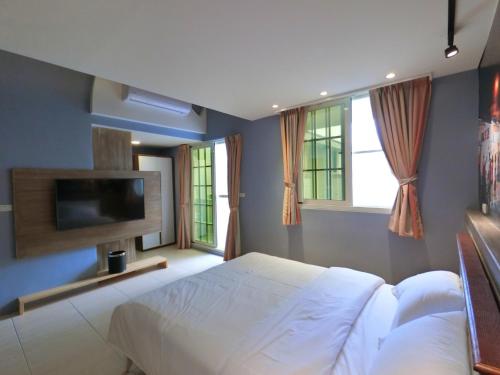 花蓮市にあるTen Minute To Go B&Bの白いベッドと薄型テレビのある寝室