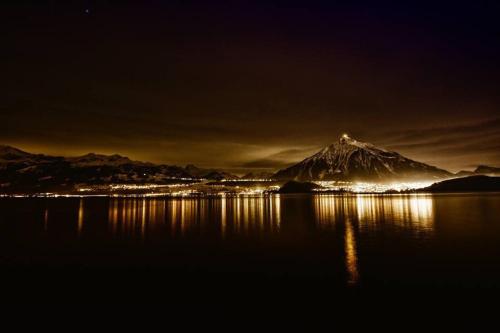 a mountain at night with its lights on the water at Otium-Oberhofen in Oberhofen am Thunersee