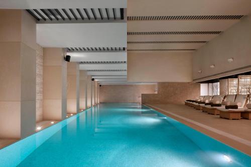 - une grande piscine avec des chaises dans un bâtiment dans l'établissement The Langham, Shanghai, Xintiandi, à Shanghai