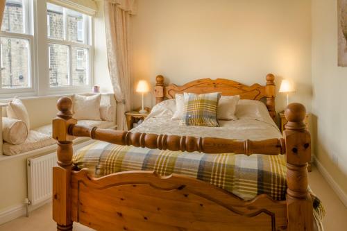 a bedroom with a wooden bed and two windows at Raikes Barn in Skipton