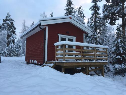 a red cabin in the snow with a bench in front at Fjällstuga in Idre