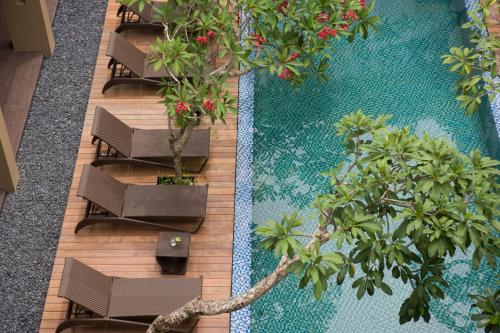 una vista sul soffitto di una piscina con sedie e alberi di Hotel Santika Kuta a Kuta