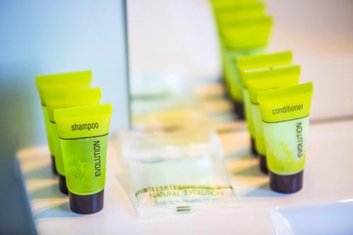 a row of green and yellow shampoo bottles on a counter at Nightcap at Rose & Crown Hotel in Elizabeth