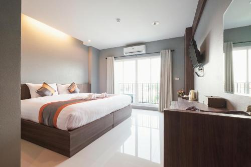 a bedroom with a large bed and a large window at Hansanan Hotel in Phitsanulok