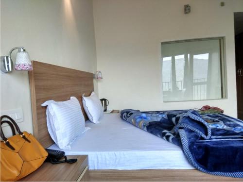 a bedroom with a bed with a blue blanket on it at Hotel Emerald Valley in Chail