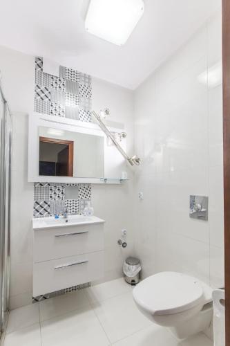 a white bathroom with a toilet and a sink at Hotel-24 in Płock
