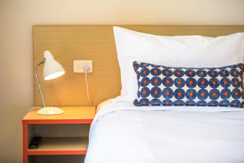 a bed with a blue pillow and a lamp on a table at Nightcap at Rose & Crown Hotel in Elizabeth