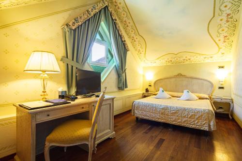 a bedroom with a bed, desk, chair and a television at Suite Hotel Nettuno in Sestri Levante