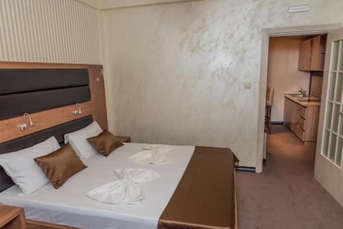 a bedroom with a bed with white sheets and brown pillows at Hotel Crnogorska Kuća in Podgorica