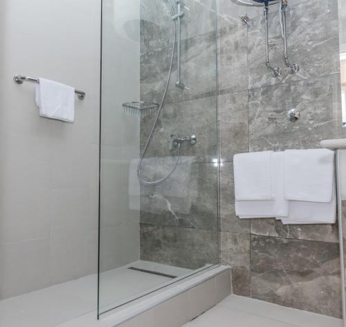 a bathroom with a glass shower with towels at Hotel Crnogorska Kuća in Podgorica
