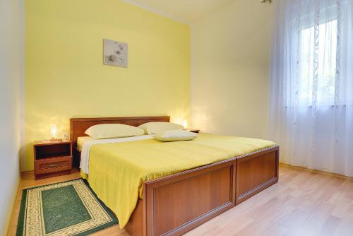 a bedroom with a bed with a yellow blanket and a window at Apartments Danilo in Medulin