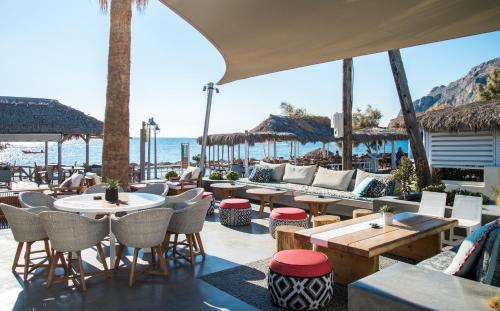 a restaurant with tables and chairs and the beach at Makris Beach Hotel in Kamari
