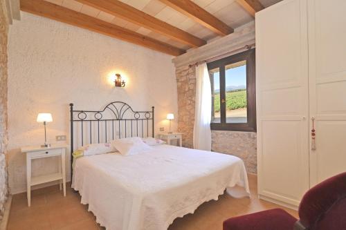 a bedroom with a white bed and a window at Villa Carratxet in Búger