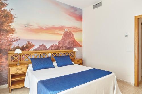 a bedroom with a bed with a mountain mural on the wall at Hostal Mar y Huerta in Es Cana