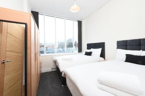 two beds in a room with a window at Slps 14 Hot Tub, Bar & Outdoor Terrace in Manchester