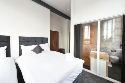 1 dormitorio con 1 cama blanca grande y baño en Stunning High Spec Sleep 14 (38 A3), en Mánchester