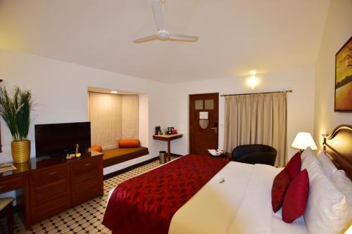 a hotel room with a bed and a television at Novotel Goa Dona Sylvia Resort in Cavelossim