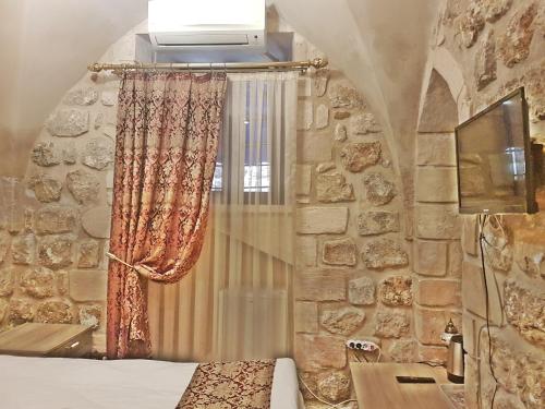 a bedroom with a stone wall with a curtain and a window at Stone Boutique Hotel in Mardin