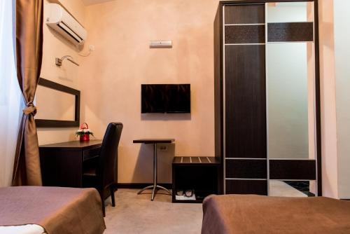 a room with two beds and a desk and a table at Hotel Crnogorska Kuća in Podgorica