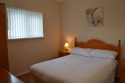 um quarto com uma cama branca e uma janela em Honeysuckle Bungalow em Torquay