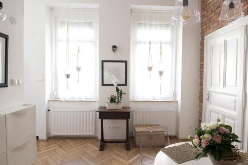 a living room with a table and two windows at NICE "TRABI" APARTMENT IN THE CITY in Budapest