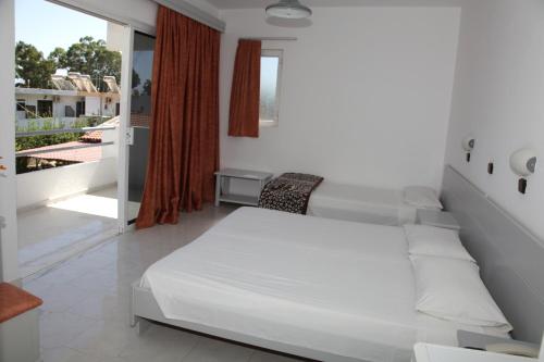 a bedroom with a white bed and a balcony at Despina Hotel in Afantou